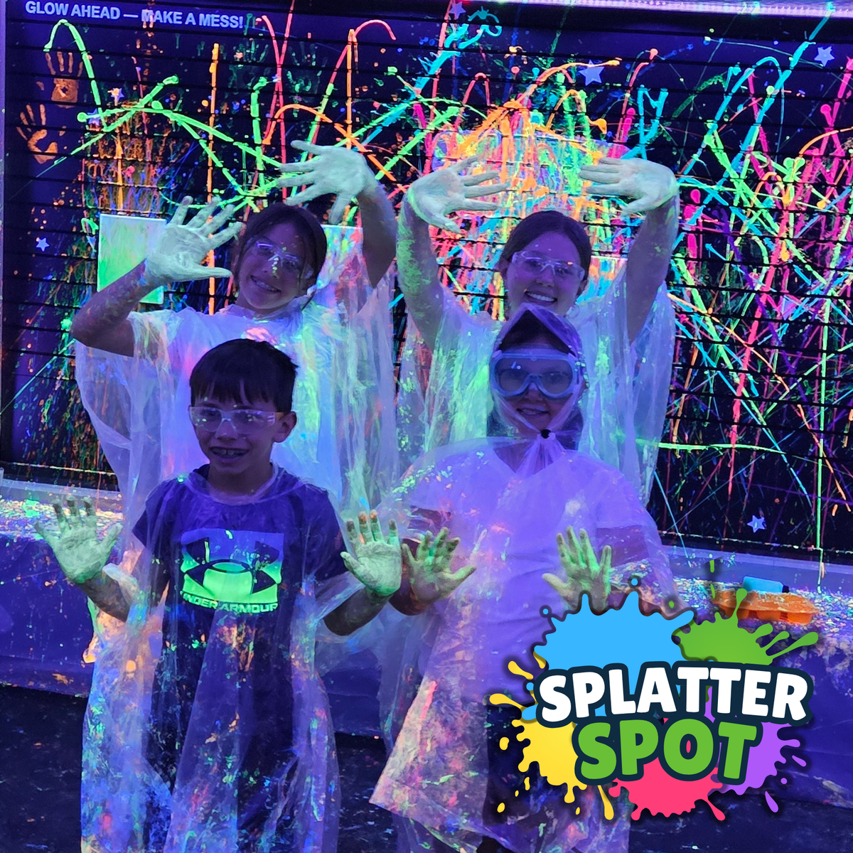 Kids with uv-reactive paint on their hands in a room with uv lights, featuring the Splatter Spot logo.